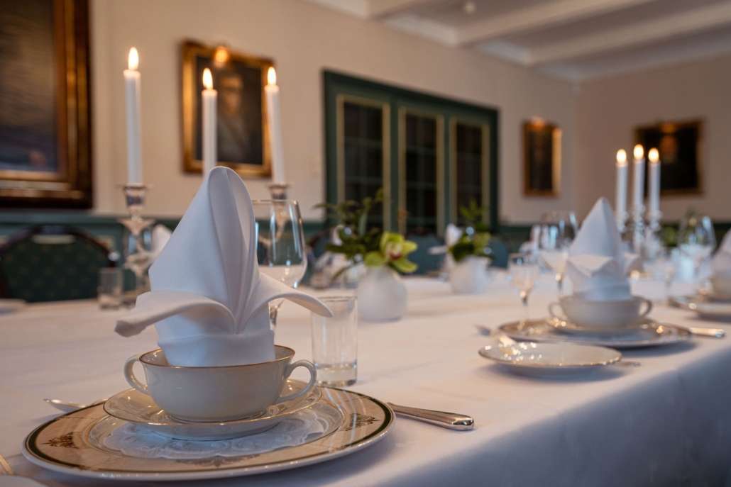 Bord dekket med hvite duker, servise, og blomster.