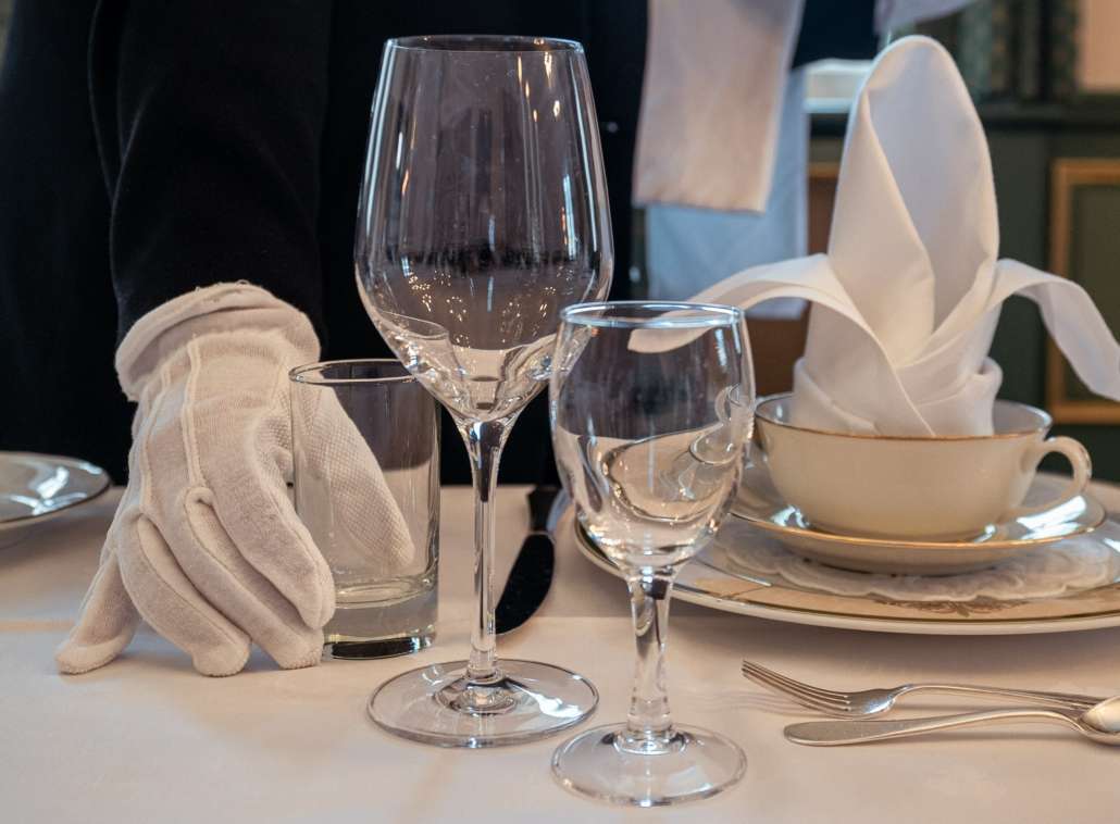 Kelner som plasserer glass og servise på bord. 